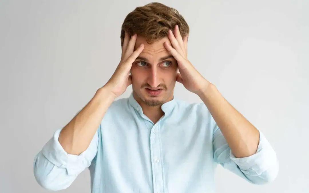 Man looking stressed with hands on head.